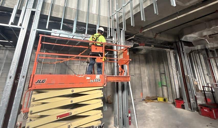 Construction worker installing interior framing and mechanical components at Boynton Beach Multifamily, demonstrating ongoing interior build-out and EB5 job creation activity.