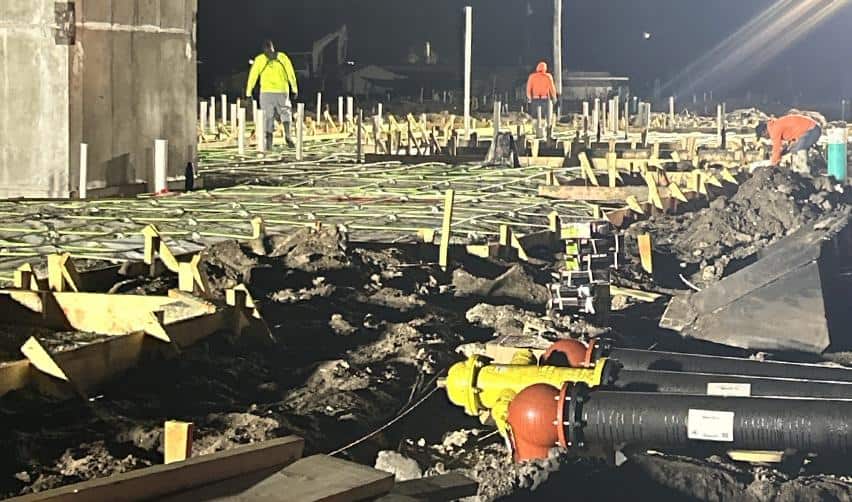 Nighttime construction activity at Terra Ceia Multifamily showing workers preparing formwork and utility connections beneath a building slab, reflecting ongoing vertical construction for the EB5 multifamily project.