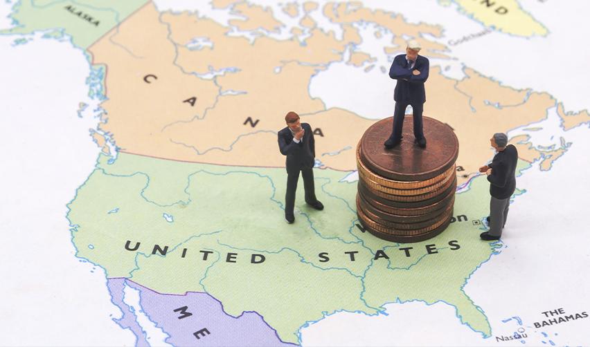 Business figures standing on stacked coins placed on a US map, symbolizing EB5 investment options and L1A and E2 visa immigration pathways.
