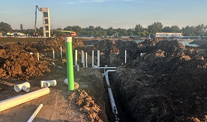 Ground-level view of underground utility installation at Terra Ceia Multifamily, with water and wastewater piping laid in trenches, highlighting site infrastructure work for the EB5 apartment project in Palmetto, Florida.