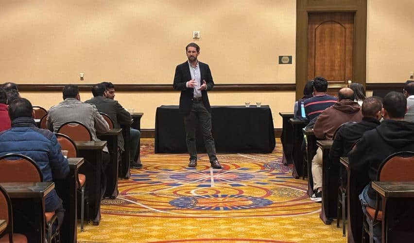 Jordan Lawrence presenting EB5 insights to a full room of attendees at an investor meetup, with families seated for the evening session.