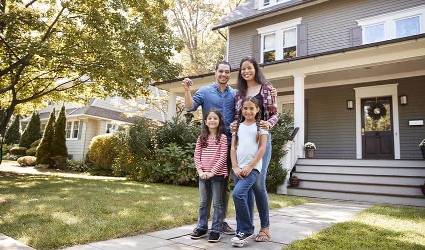 A family standing in front of a completed single-family home, representing simple EB5 real estate projects with clear demand and familiar business models.