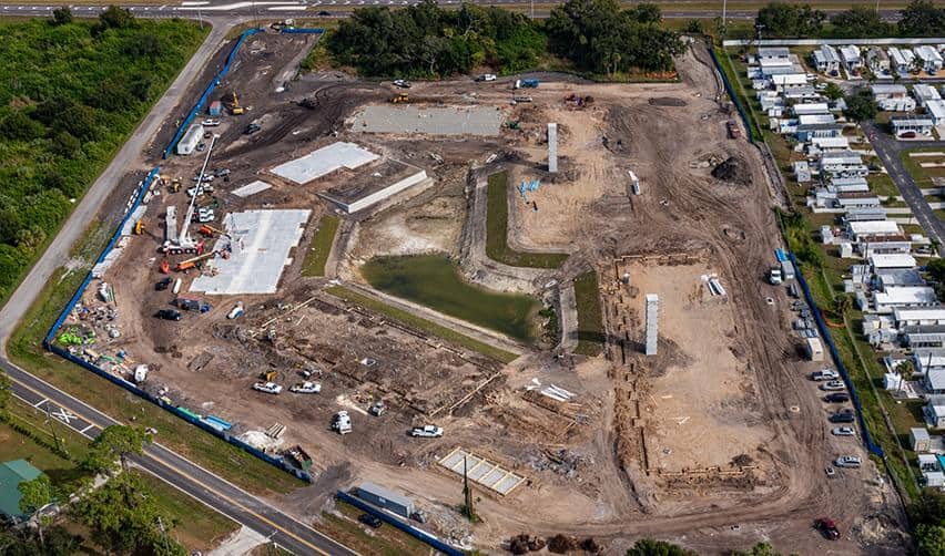 Wide aerial perspective of Terra Ceia Multifamily development site with multiple completed slabs, stormwater pond, and surrounding roads and residential areas, demonstrating coordinated site work and EB5 project scale in Palmetto, Florida.