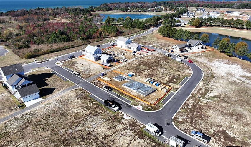Aerial photo of Bay Creek showing multiple homes under construction, new roadways, and crews working near the shoreline.