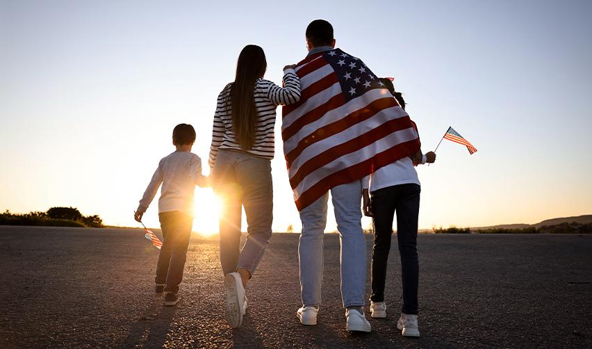 A family walking toward the sunset with a US flag, representing EB5 investors seeking long-term residency and a future in the United States.