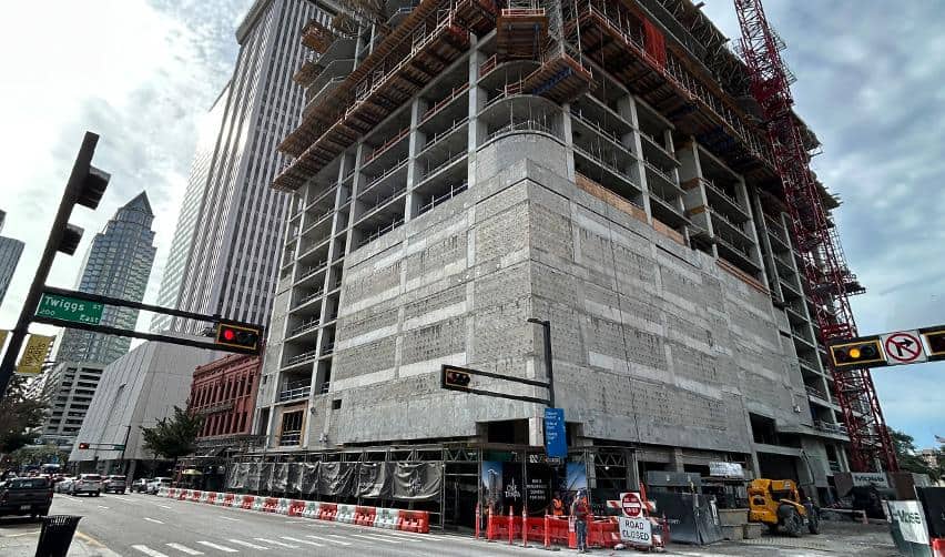 Lower-level exterior of ONE Tampa showing completed concrete structure and scaffolding, marking continued construction momentum for the EB5 project.
