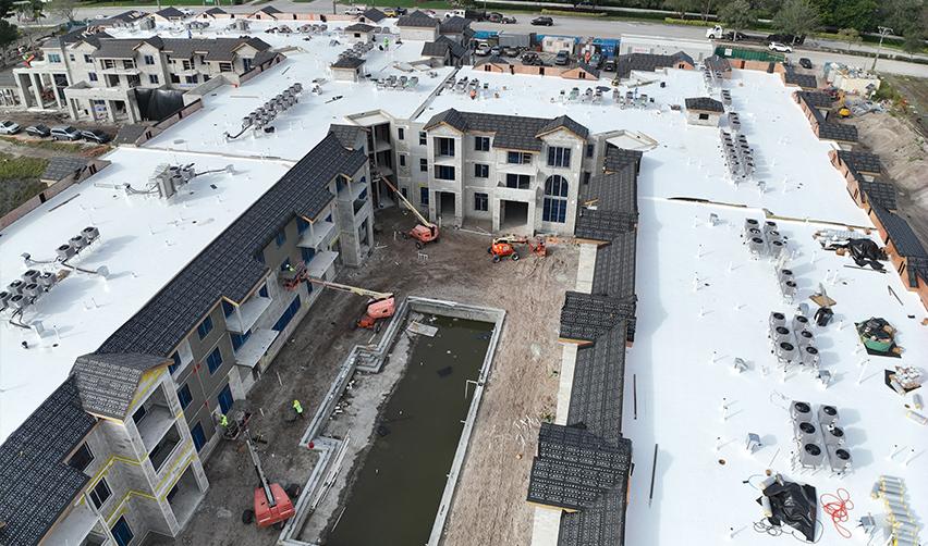 Aerial view of Boynton Beach Multifamily under construction, showing completed roofing systems, rooftop equipment installation, and active interior courtyard work supporting EB5 job creation.