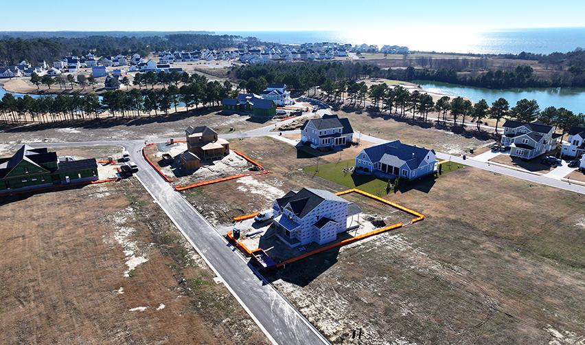 Drone image of newly constructed and in-progress homes at Bay Creek, with coastal ponds and open lots visible, demonstrating steady residential buildout within the rural EB5 project.
