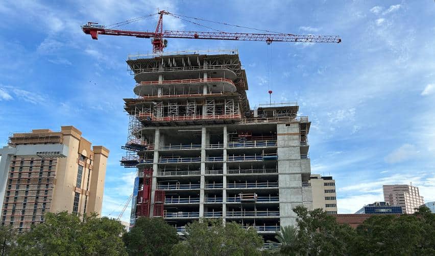 Street-level view of ONE Tampa under construction with tower crane and exposed concrete floors, reflecting steady advancement of the EB5 urban development.