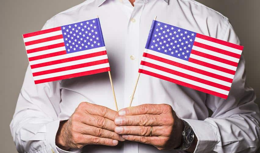 Hands holding two U.S. flags, symbolizing the EB5 immigrant investor journey toward U.S. permanent residency and long-term settlement.