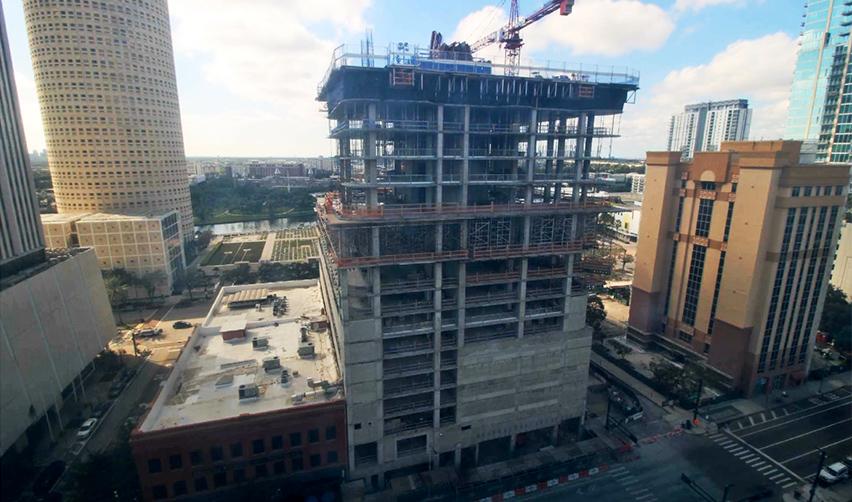 Aerial view of the ONE Tampa tower under construction in downtown Tampa, showing the concrete structure rising through upper floors as part of an active EB5 real estate development.