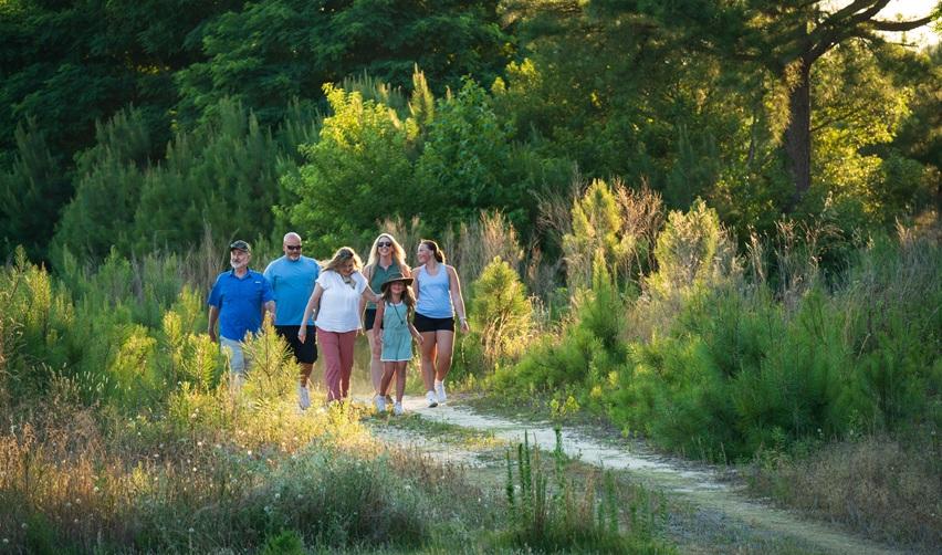 Residents walking together along a wooded trail in Bay Creek’s Nature Preserve during a guided community hike.