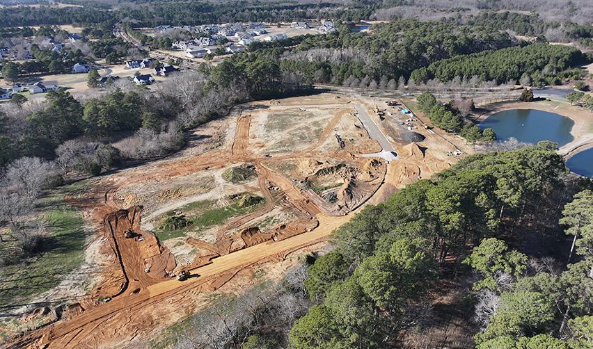 Aerial photo of active site grading and earthwork at Bay Creek, with heavy equipment preparing future residential lots surrounded by pine forests, reflecting early-stage development progress for EB5 investors.
