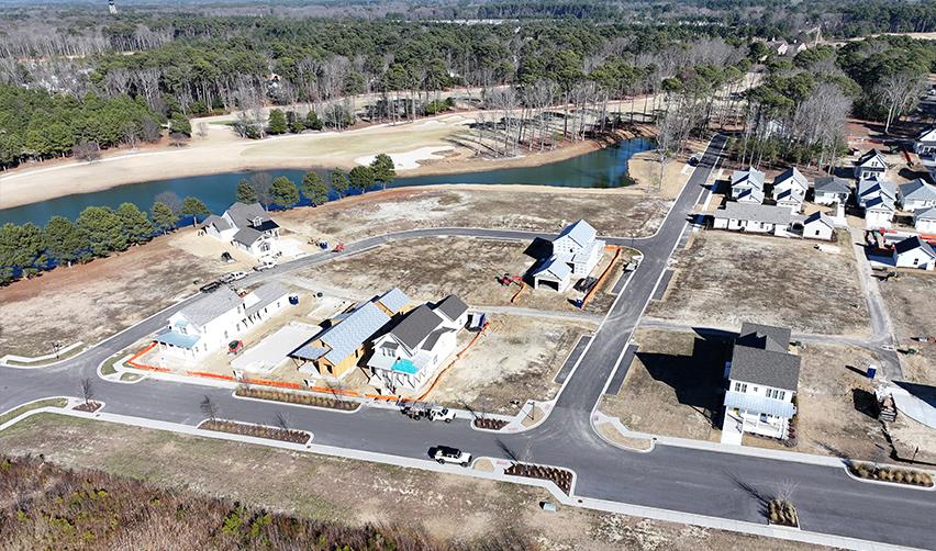 Drone image of Bay Creek homes under construction along paved streets and waterfront ponds, highlighting active residential development and infrastructure work within the rural EB5 project.