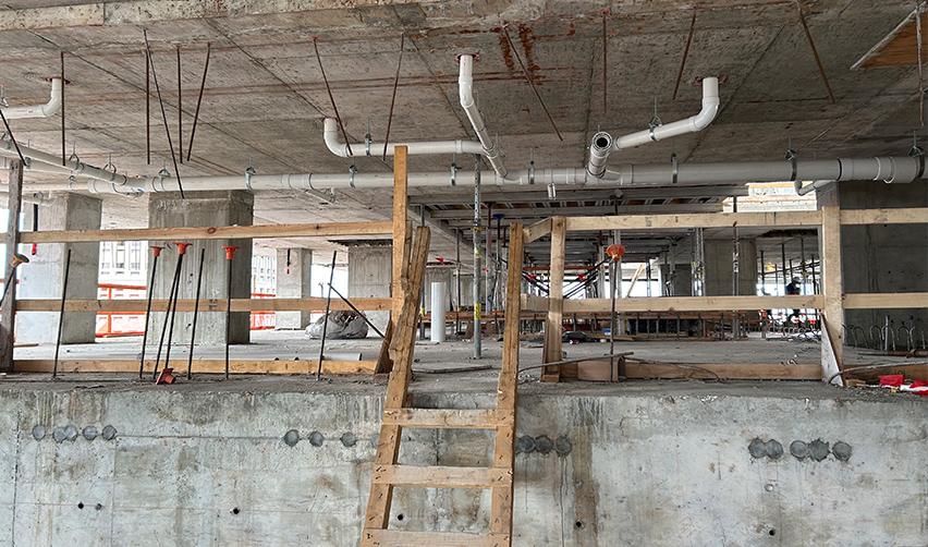 Interior construction at ONE Tampa featuring installed plumbing lines and early mechanical systems, highlighting ongoing EB5 project infrastructure work.