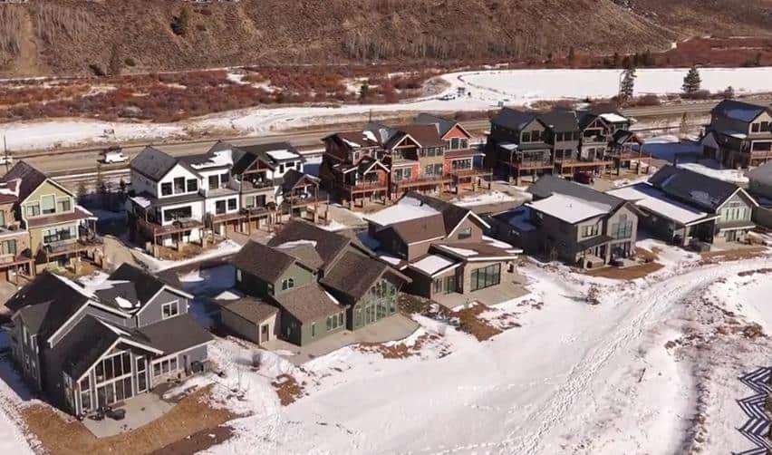 Drone perspective of residential neighborhoods at Grand Park with multiple finished homes, snow-covered lots, and surrounding open space, reflecting continued delivery of housing tied to EB5 job creation.