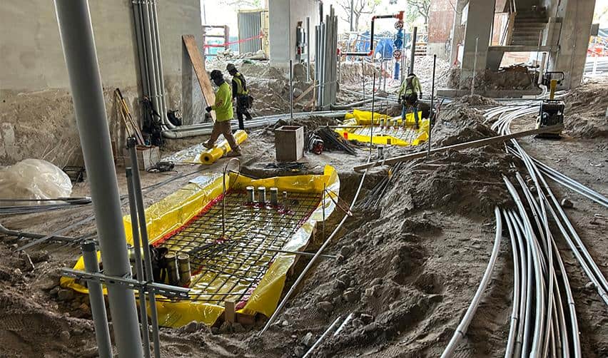 Workers installing underground utilities and structural reinforcements at ONE Tampa, demonstrating continued job creation and infrastructure activity for the EB5 project.
