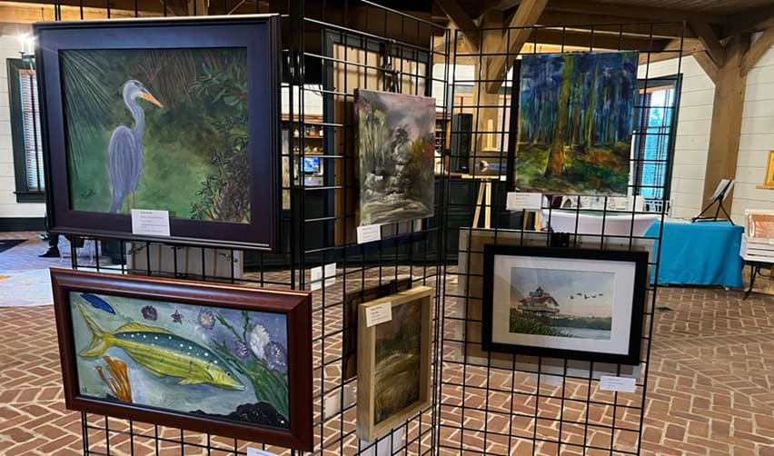 Framed paintings displayed at the Bay Creek artist exhibition in Chesapeake Hall, highlighting cultural programming and community engagement valued by EB5 investors.