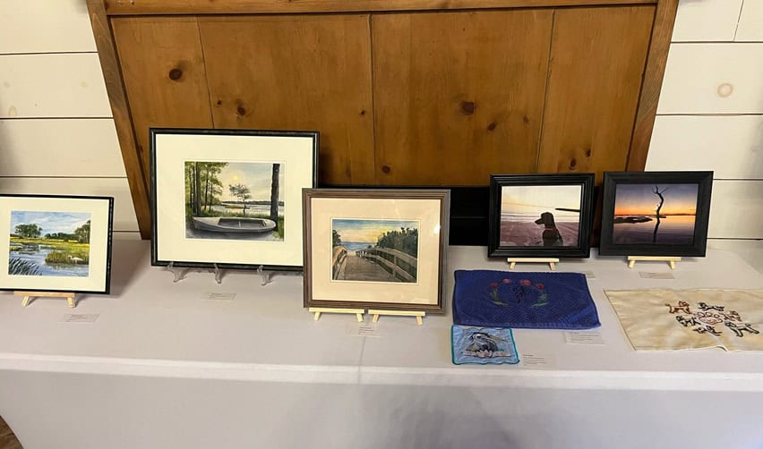 A curated table of local artwork at Bay Creek’s January artist exhibition, showcasing creative expression and the community’s vibrant cultural life tied to EB5-supported development.