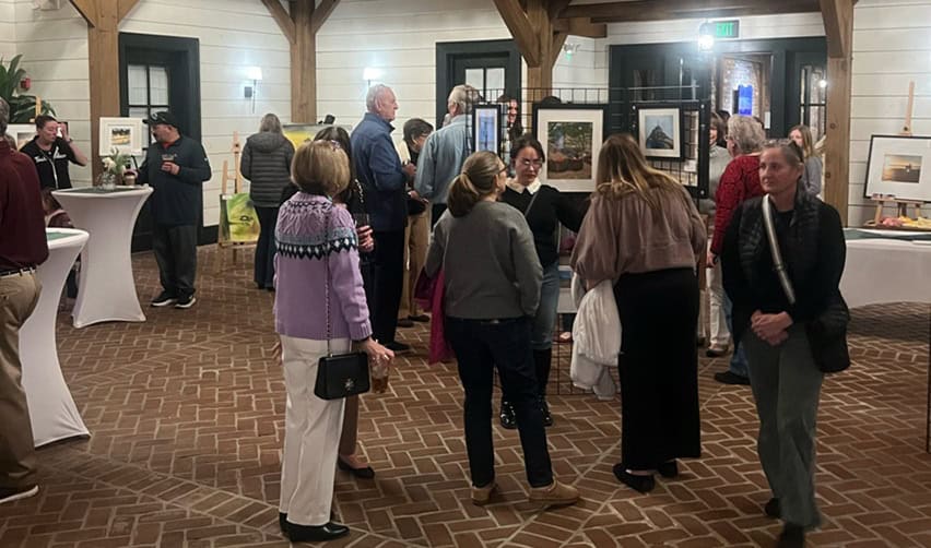 Guests socializing among art displays during the Bay Creek artist exhibition, illustrating active resident participation and a lived-in community environment attractive to EB5 investors.