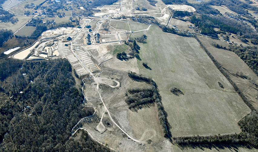 Wide aerial view of the Rocky River EB5 rural development site, highlighting expanding road networks, graded lots, and surrounding open land planned for a 55+ residential community.