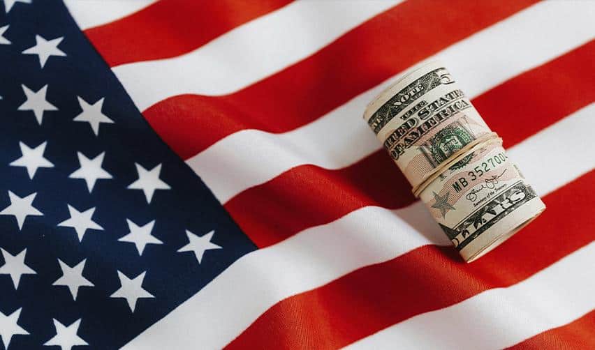 Rolled US dollar bills placed on an American flag, symbolizing EB5 investment capital, US immigration opportunities, and financial commitment toward a US Green Card.