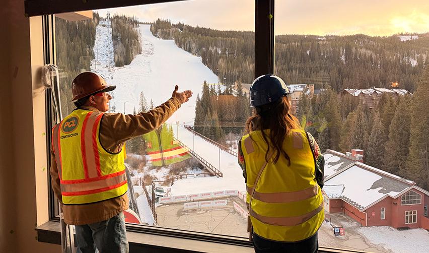 Two construction managers in safety gear reviewing final progress inside Kindred Resort at Keystone, overlooking ski slopes and gondola access, highlighting late-stage construction of a rural EB5 resort project.