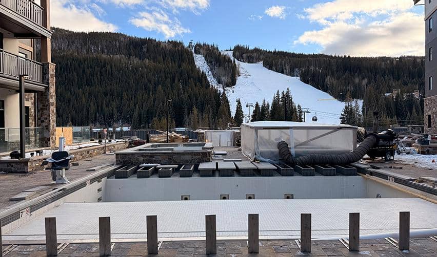 Outdoor pool area at Kindred Resort at Keystone under final construction, with surrounding lodge buildings and mountain terrain reflecting late-stage progress on a rural EB5 investment project.