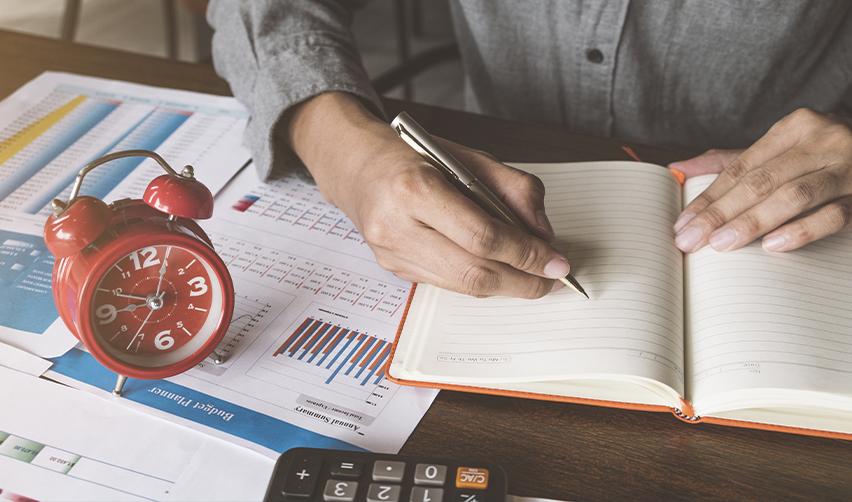 An EB5 investor planning their investment strategy with a clock on the desk, representing processing time differences between rural vs urban EB5 projects.