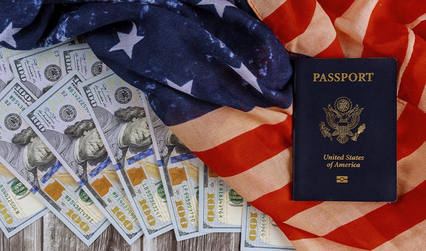 US passport placed on U.S. flag with $100 bills, symbolizing EB5 investment and the path to American permanent residency.