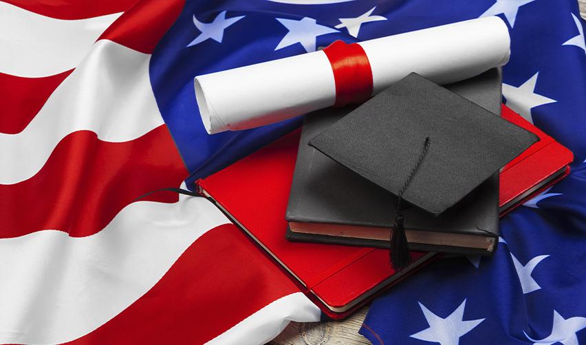 Graduation cap, diploma, and books on an American flag, symbolizing education and future career pathways available to children of EB5 investors in the United States.