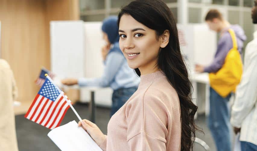 Young woman holding a small U.S. flag, representing new opportunities for EB5 families building careers and lives in the United States.