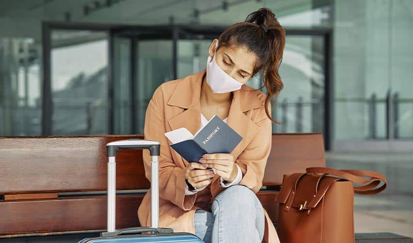 Foreign investor reviewing passport and travel documents while waiting at airport during EB5 green card process.
